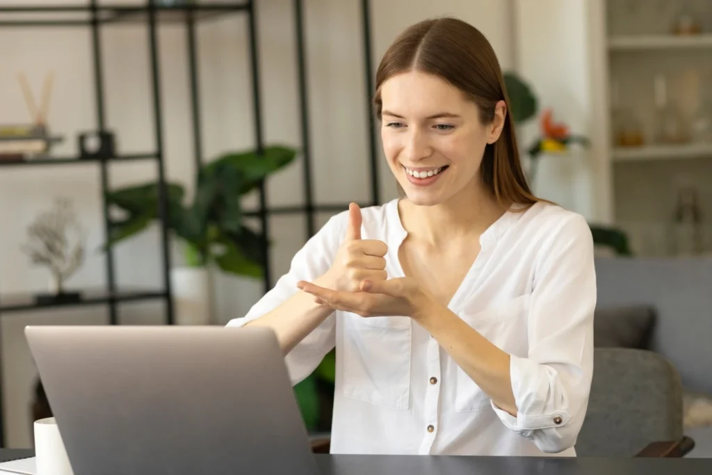 Woman using sign language to communicate over video call on laptop